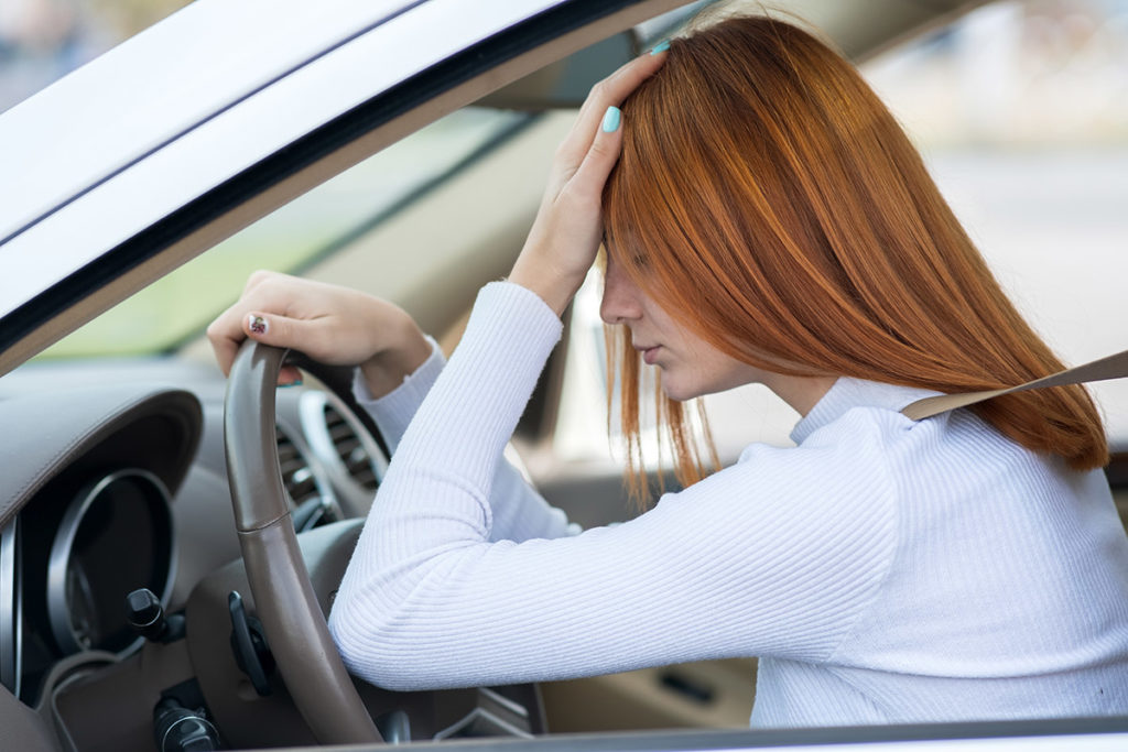 woman driving holder her head from drinking and driving consequences