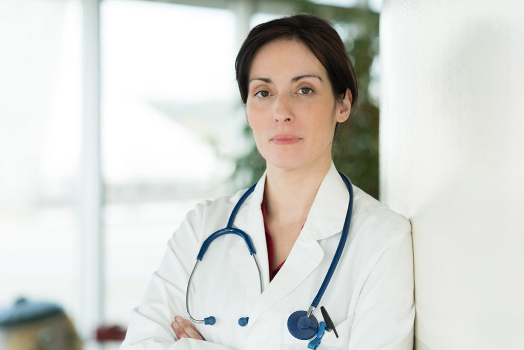 doctor leaning against wall concerned about Oxycodone vs Hydrocodone abuse