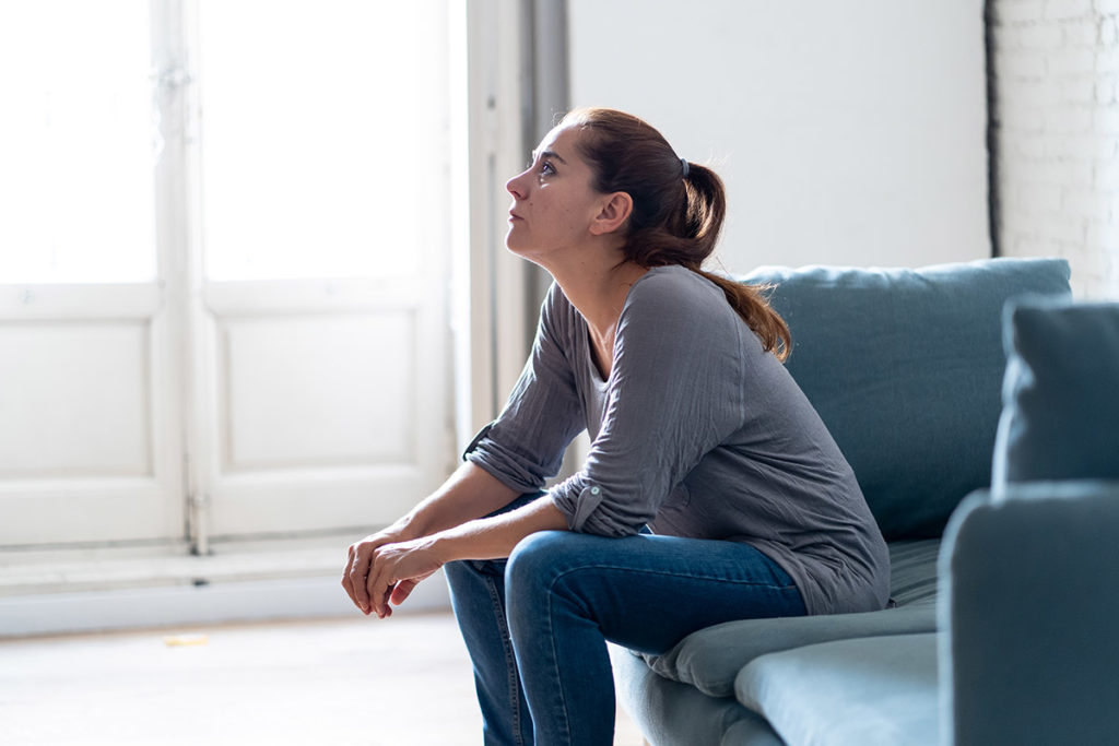 woman staring off sitting on couch wondering Who Needs Drug Detox Programs