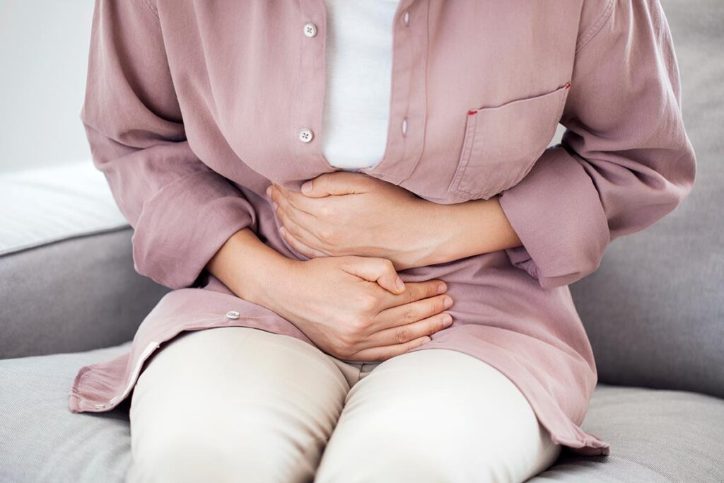 a woman holding her stomach considers alcohol and gastritis
