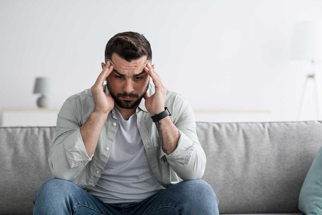 Person on couch struggling with lack of family support and addiction recovery