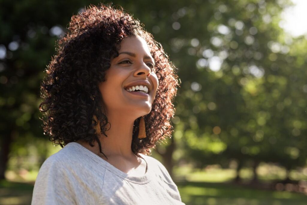 Woman smiling on a bright sunny day due to success in addiction treatment