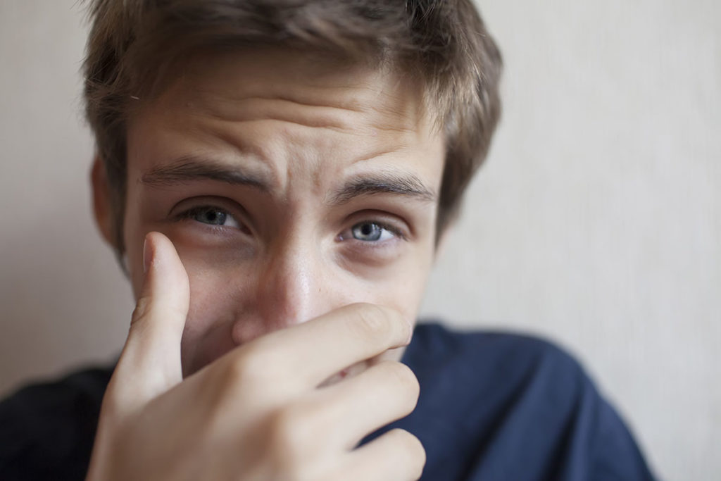 man with hand over face dealing with addiction and mental illness