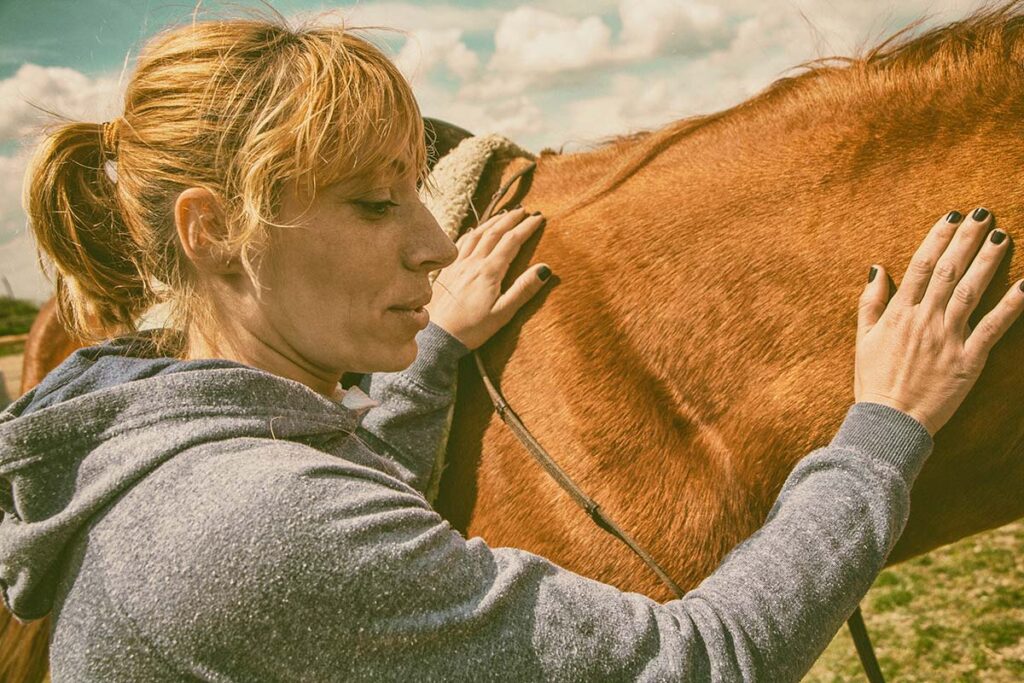 a person explores the benefits of equine therapy by petting a horse