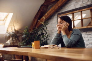 a person sits sadly at a table recognizing the link between PTSD and eating disorders