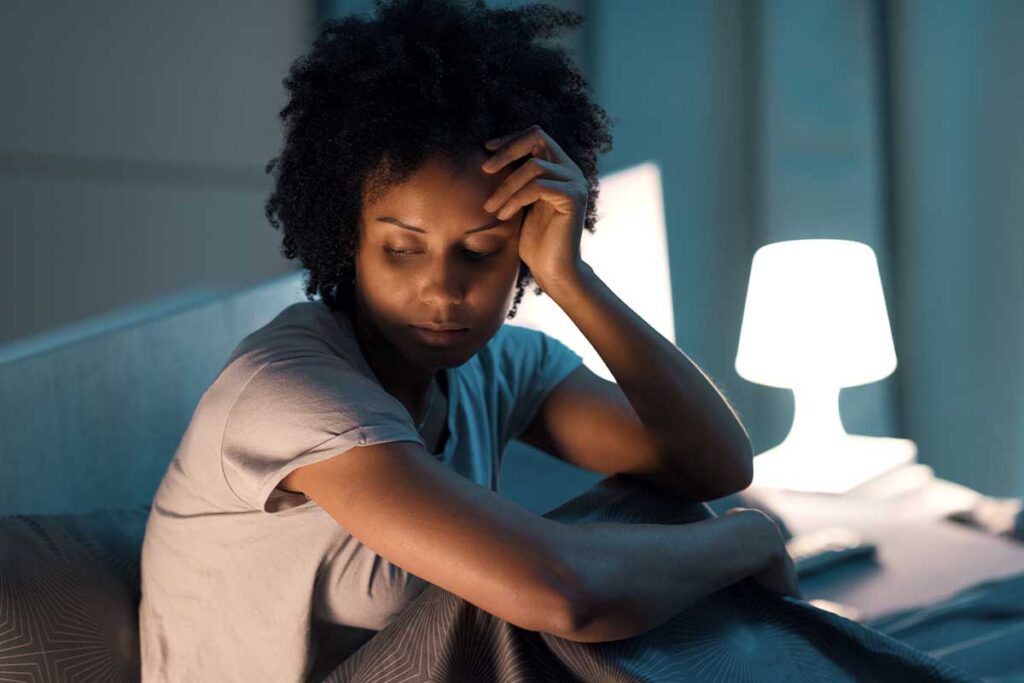 a woman in bed looks sad after pondering women's alcohol abuse