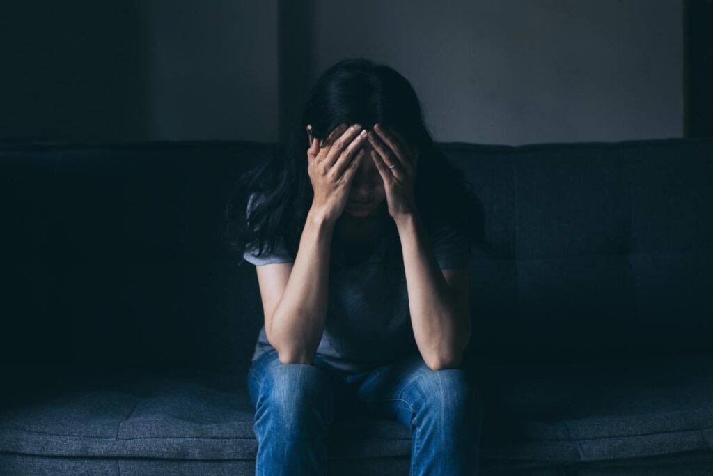 Woman sitting with her head in her hands feeling distressed about behavioral addictions