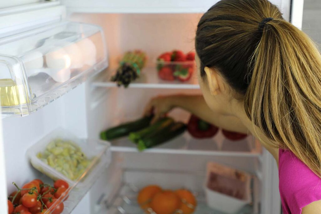 a person looks inside a refrigerator pondering the link between nutrition and depression