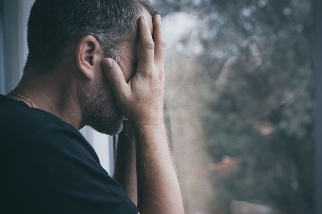 a man covers his face as he considers rates of suicide in injection drug users