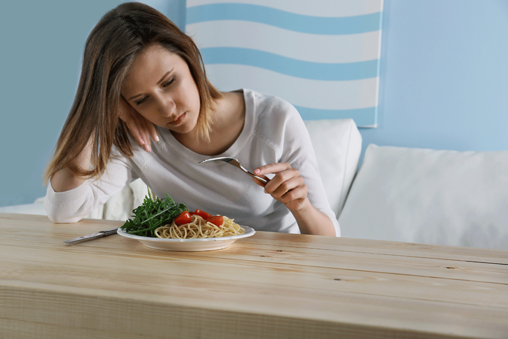 Person picking at food while experiencing an eating disorder in college