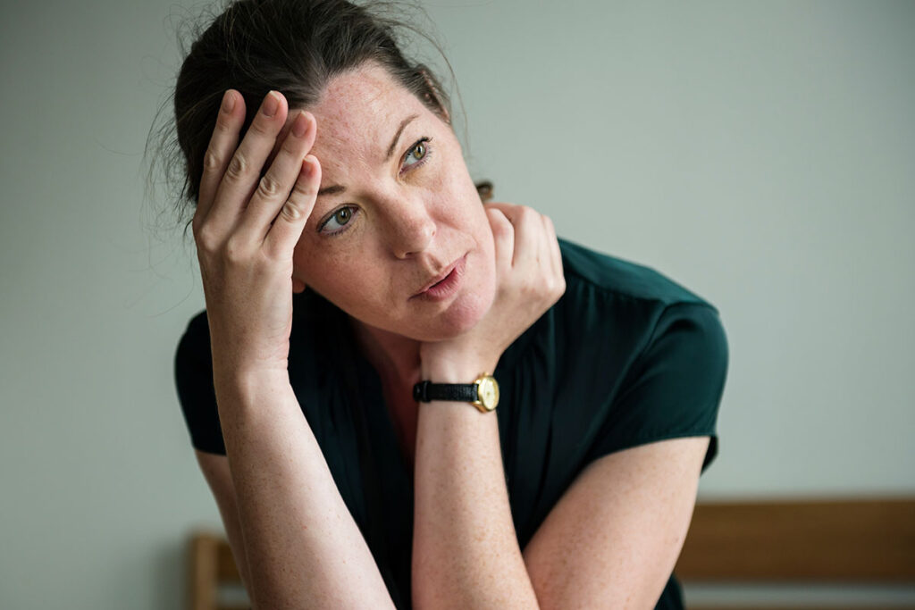 a woman holds her head as she considers the health risks of rapid detox