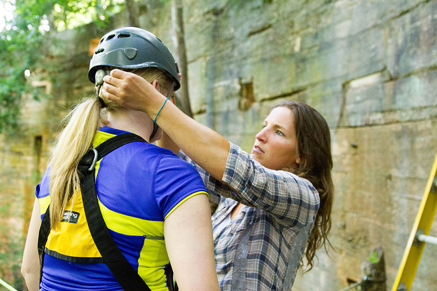 woman putting helmet on another woman's head before doing rock climbing