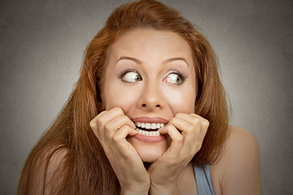 Scared looking women biting her fingernails