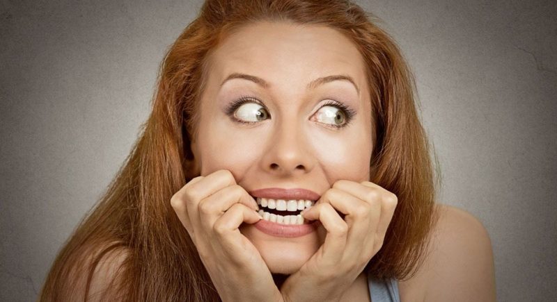Scared looking women biting her fingernails