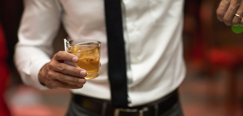 business man holding an alcoholic beverage