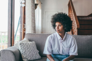 person sitting on couch looking out window while contemplating symptoms of borderline personality disorder