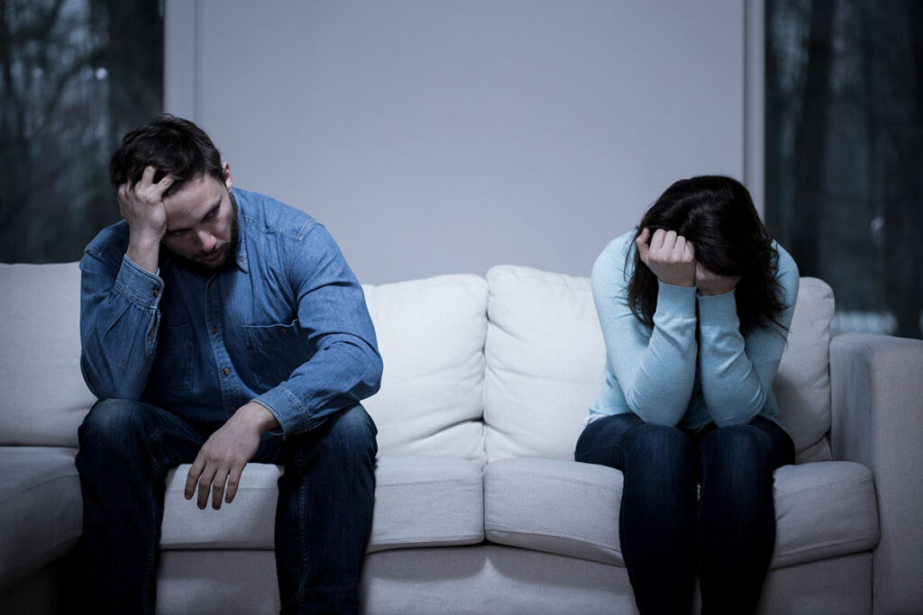 Couple on couch sitting away from each other as exemplary of women and relapse caused by relationships