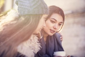 one young female reassures another outside an anxiety treatment center