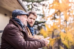 young patient talks to older man outside in the fall during their drug addiction treatment program