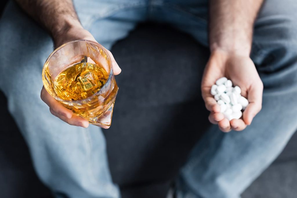 a man looking at a glass of whiskey and pills without thinking about alcohol and dopamine