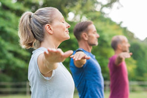 meditation therapy program, people with their eyes closed and arms out meditating outdoors