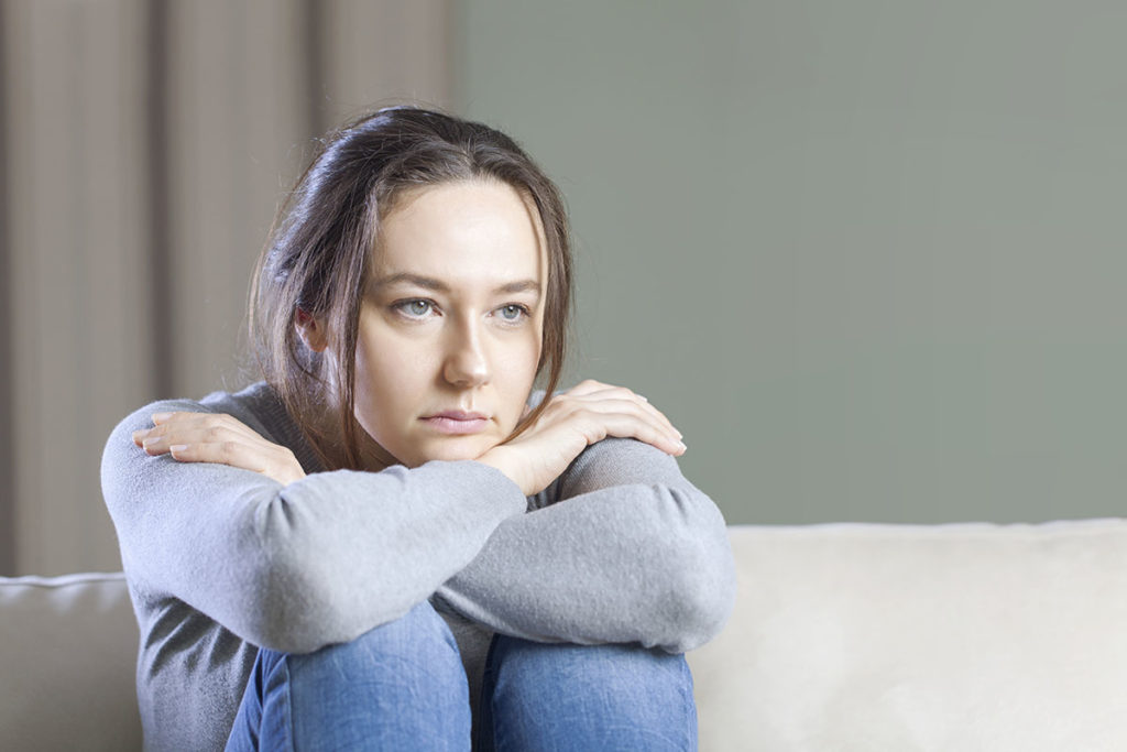 a woman on her couch sitting and wondering how addictive is alcohol