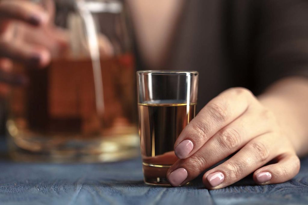 am I an alcoholic, close up of a shot glass filled with brown liquor