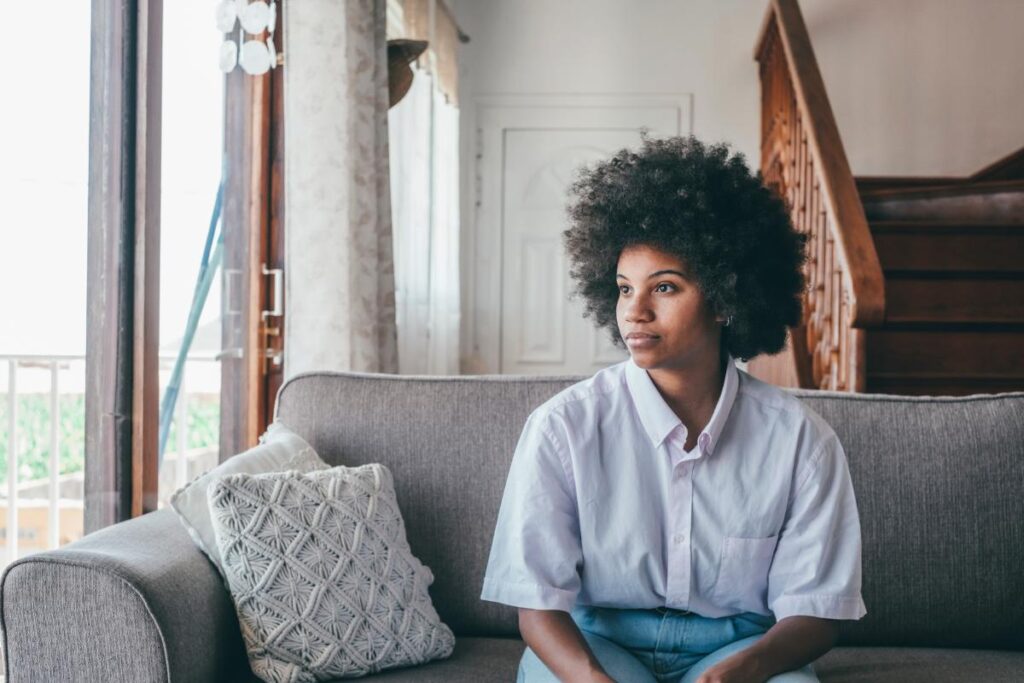 woman peering out the window while sitting on a couch in behavioral therapy for smoking