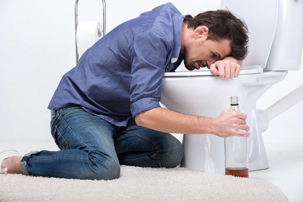 man sick from alcohol at toilet experiencing dangers of substance abuse