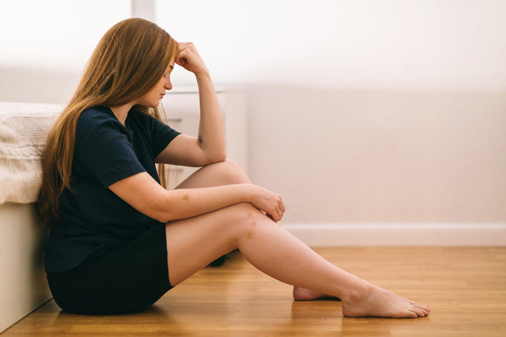 woman sitting on floor dealing with signs of codependency