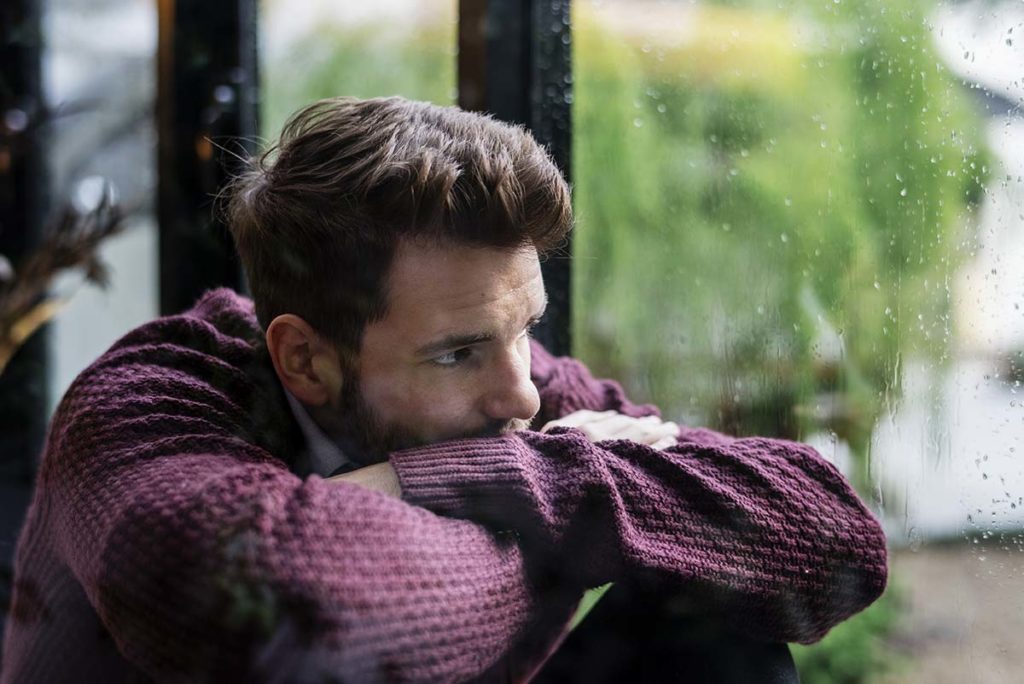 man resting on his folded arms wondering about the stages of alcoholism