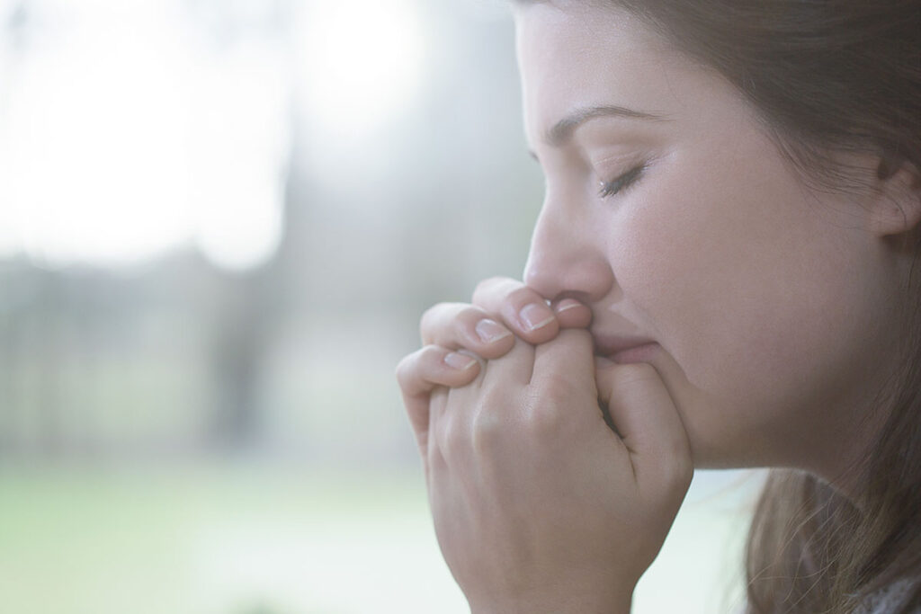 a woman cries holding her mouth possibly struggling with the links between women and trauma