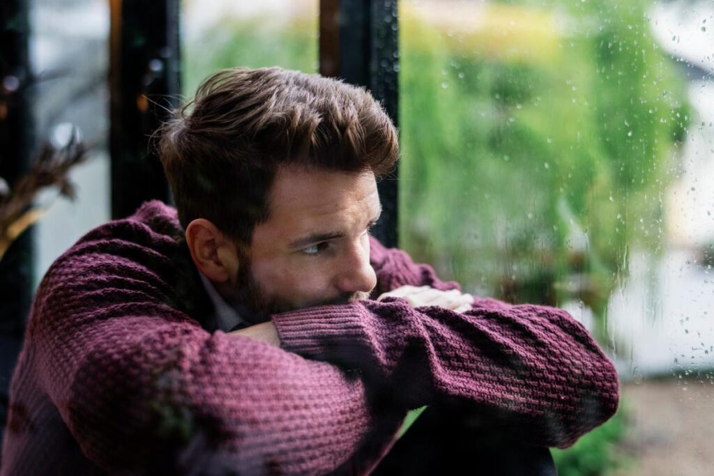 Man looking out window struggling with unhealthy thinking