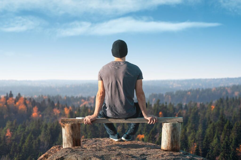 Man enjoying the view from the top of a mountain after prioritizing addiction recovery