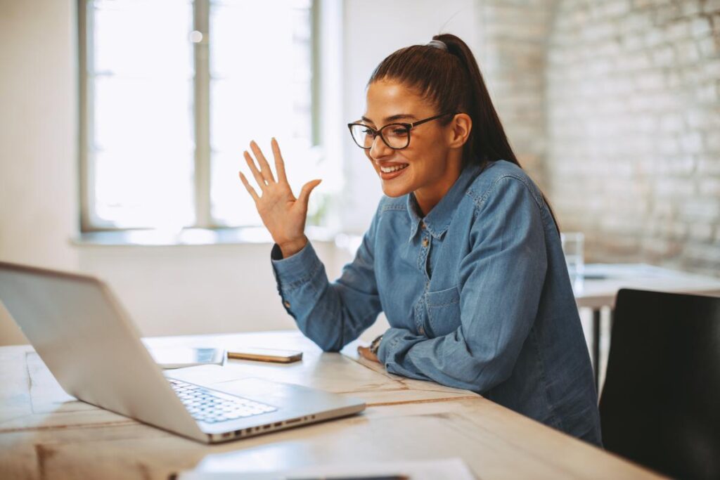 a person in a virtual IOP waves at their laptop