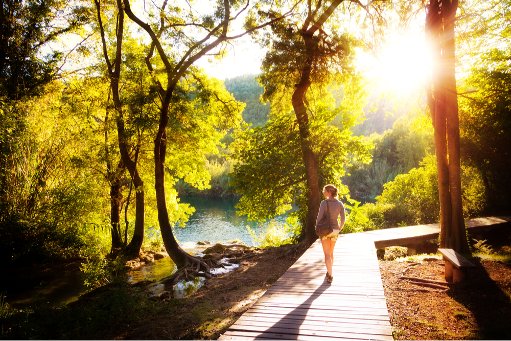 Woman walking in the sunshine on wooded path