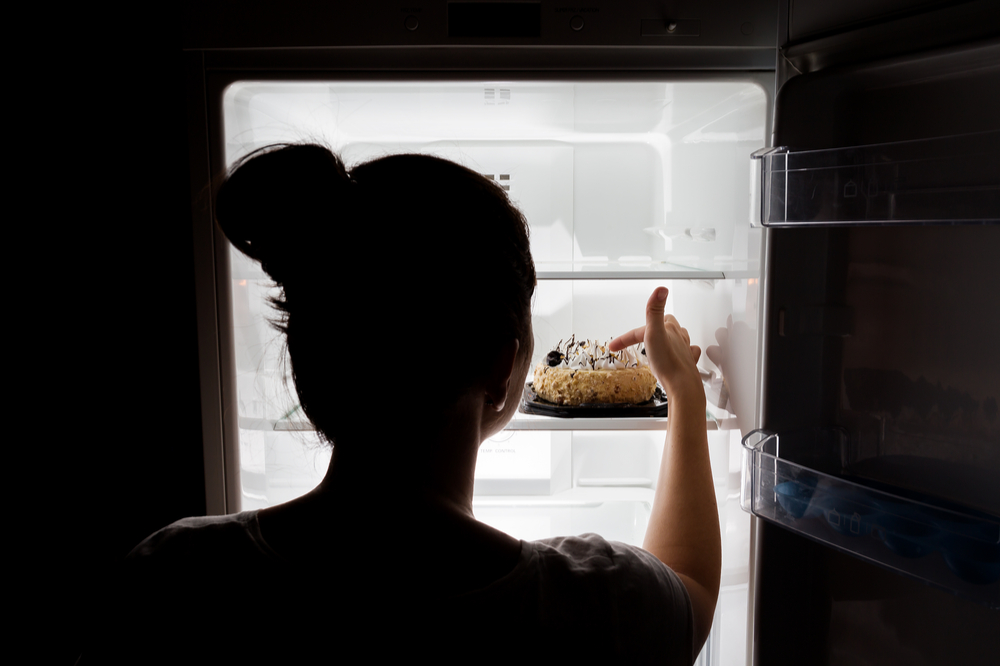 Woman at the fridge experiencing sugar cravings in her recovery process