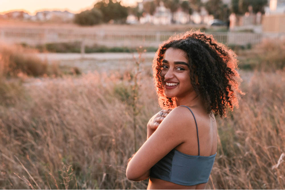 Woman smiling out in field from radical acceptance and dbt