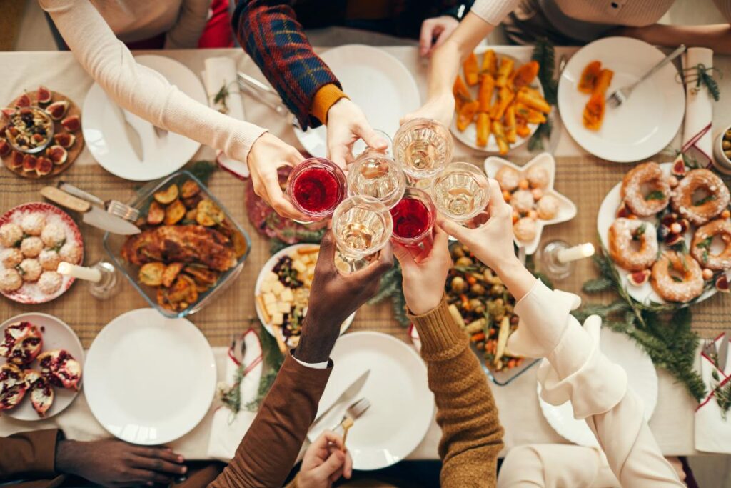 a group of people touch drinks over a holiday feast, a reminder to be mindful of drinking cues