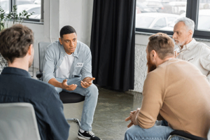 a group of men talk in a circle in a men's alcohol rehab center