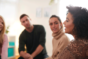 a group listens as someone talks in an opiate addiction treatment center