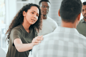 Concerned woman comforting another patient in group therapy during polysubstance abuse treatment