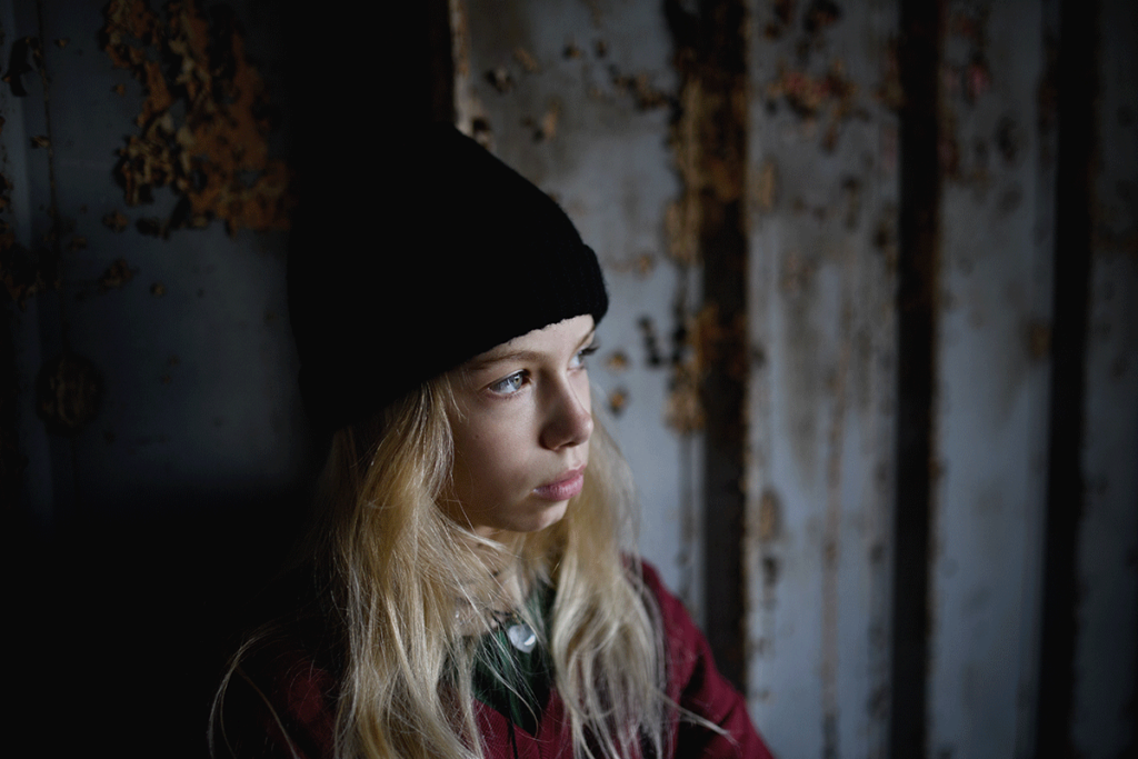 Person in dark room looking out window while struggling with addiction to roxies