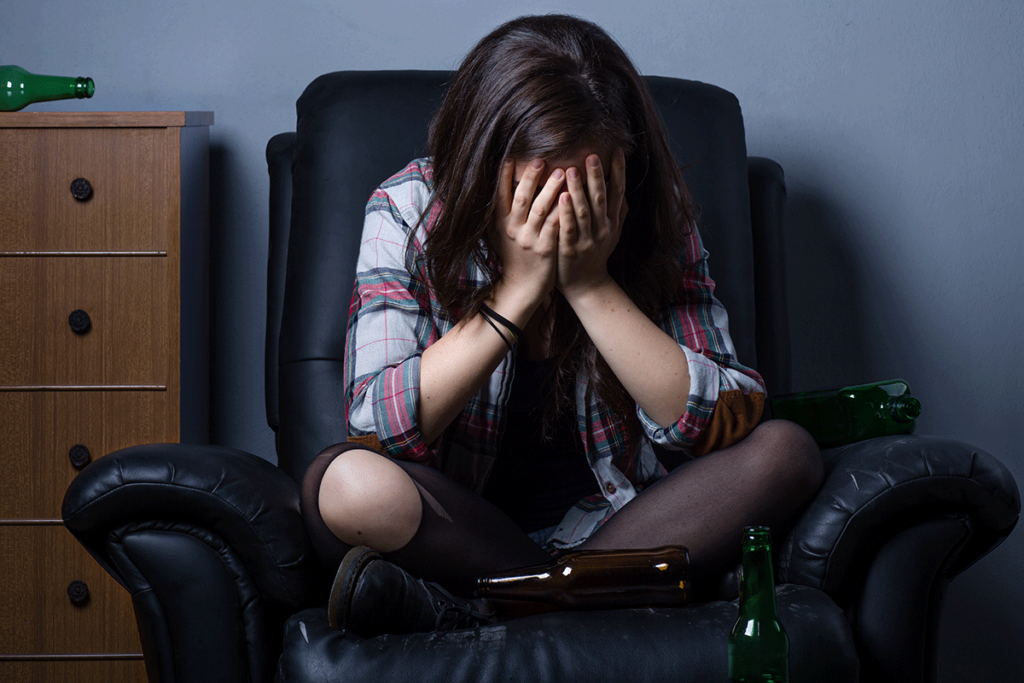 Woman sitting in chair with hands covering face wondering how many drinks are too many