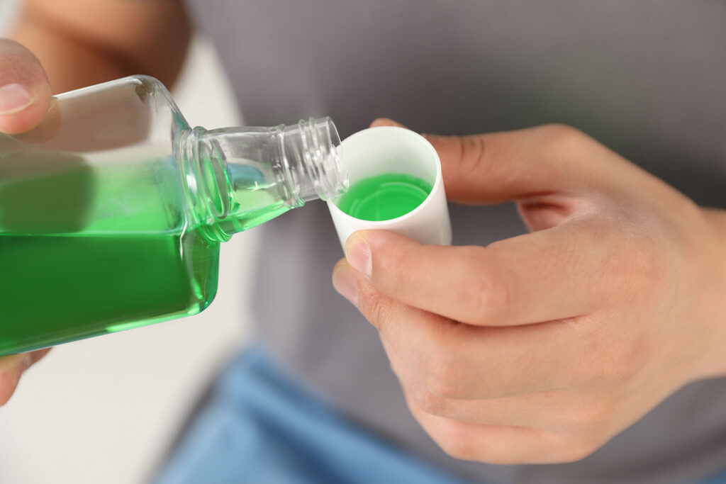 person pouring green mouthwash while wondering can mouthwash cause a relapse