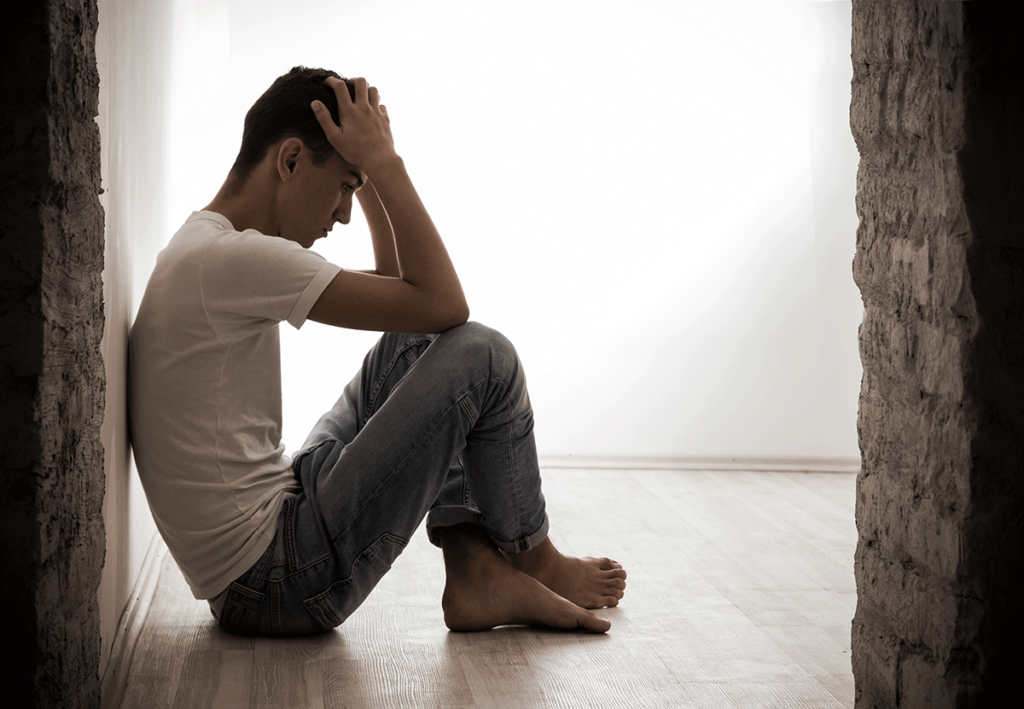 person sitting against wall hanging head while pondering the question are mothballs addictive