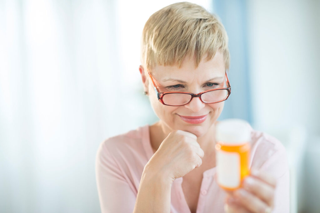person closely inspecting pill bottle with a mischievous grin wondering is clonazepam addictive