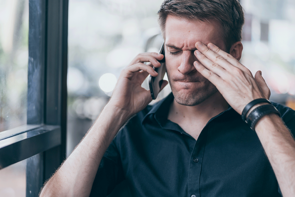 person on phone struggling with tension headache while trying to find answers to the question what are the signs of anger
