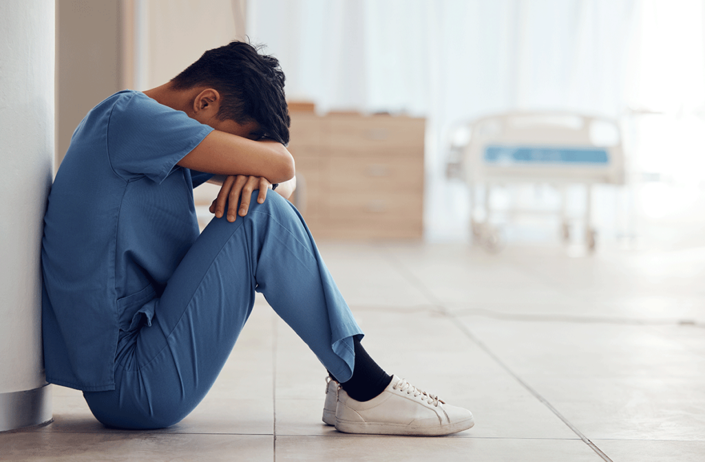 nurse at work sitting against wall with head between knees while trying to find answers to the question what is high functioning depression