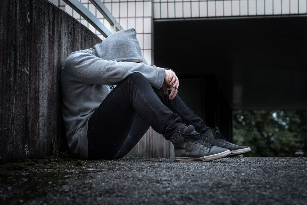 person sitting against wall in dark alley wondering what is ice cream slang for